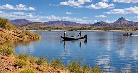 Two anglers standing and fishing from a bass boat on Alamo Lake with desert mountains in the background