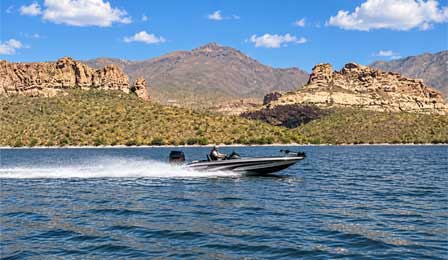 Bass boat traveling across Apache Lake with rugged Arizona desert mountains