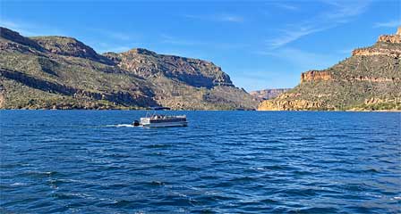 Pontoon boat on Apache Lake surrounded by rugged Sonoran Desert mountains in Arizona