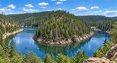 Kayakers on Blue Ridge Reservoir winding between pine-covered canyon walls in Arizona