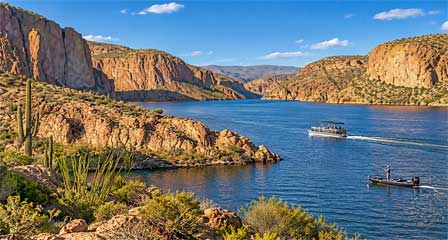 Boats cruising on Canyon Lake Arizona surrounded by rugged desert canyon cliffs