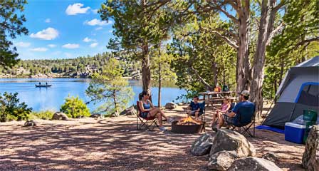 Family camping beside Fool Hollow Lake among ponderosa pine trees with a tent, camp chairs and lake views near Show Low Arizona