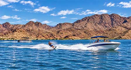 Water skiing and pontoon boat cruising Lake Havasu with desert mountains in the background