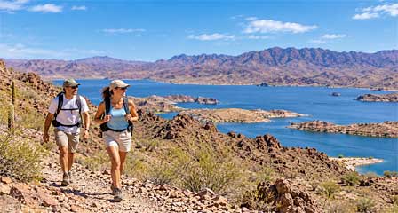 Two hikers exploring rocky desert mountain trails overlooking Lake Havasu Arizona