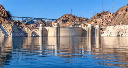Hoover Dam and its intake towers viewed from Lake Mead between steep desert canyon walls