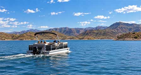 Pontoon boat cruising across Lake Pleasant with blue water and Sonoran Desert mountains northwest of Phoenix Arizona