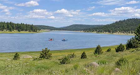 Mormon Lake Arizona with water surrounded by grassy shoreline and pine-covered hills